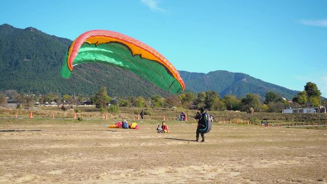 A man prepares his glider for his next paragliding flight around the mountains.