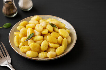 Homemade Easy Potato Gnocchi on a Plate on a black background, side view. Copy space.