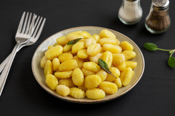 Homemade Easy Potato Gnocchi on a Plate on a black background, side view.