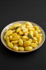 Homemade Easy Potato Gnocchi on a Plate on a black background, side view.