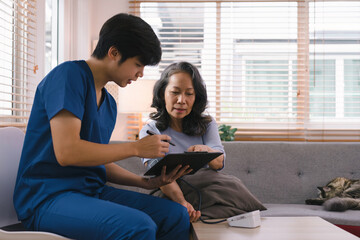 Young Asian male nurse, assisted living in-home carer, or doctor visiting an old senior citizen at home to talk about result follow-up checklist, healthcare advice, or prescription.