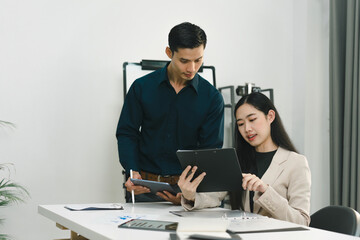Two coworkers having a friendly discussion in the modern office about a new project.