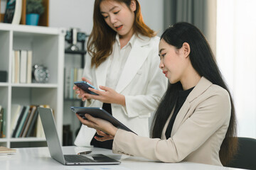 Two professional millennial Asian startup businesspeople are discussing evaluation data in a...