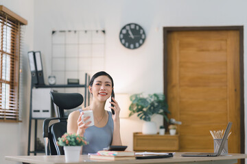 A portrait of a beautiful, professional, and confident millennial Asian businesswoman making business calls at home office.