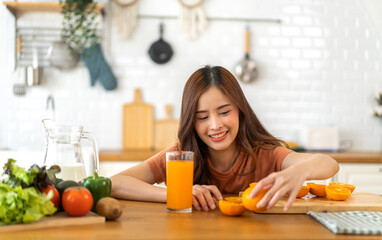 Portrait of beauty body slim healthy asian woman drinking glass of juice and orange.young girl preparing cooking healthy drink with fresh orange juice in kitchen at home.Diet concept.healthy drink