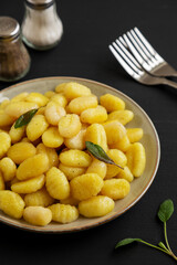 Homemade Easy Potato Gnocchi on a Plate on a black background, side view.