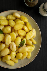 Homemade Easy Potato Gnocchi on a Plate on a black background, top view. Flat lay, overhead, from above. Close-up.