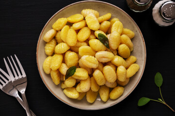 Homemade Easy Potato Gnocchi on a Plate on a black background, top view. Flat lay, overhead, from above.