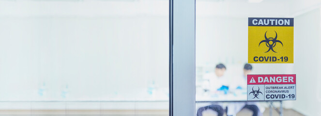 Banner Biohazard disease alert corona outbreak sign on glass wall laboratory science center. Wide shot Medical care clinic with hazard alert sign with copy space. Medical Healthcare concept.