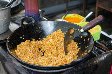 The process of cooking Javanese fried rice by a cook or chef over a large hot skillet. Nasi goreng jawa (Indonesian for Javanese fried rice, Javanese: sega goreng jawa) is fried rice from Java. - obrazy, fototapety, plakaty