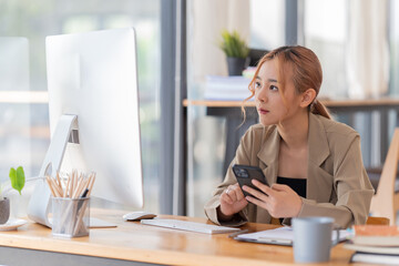 appy young businesswoman Asian siting on the chairs cheerful demeanor raise holding coffee cup smiling looking laptop screen .Making opportunities female working successful in the office.