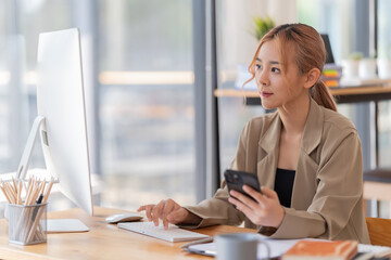appy young businesswoman Asian siting on the chairs cheerful demeanor raise holding coffee cup smiling looking laptop screen .Making opportunities female working successful in the office.
