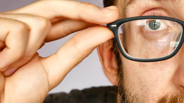 Close-up of the face of a man taking off the glasses and then putting them on again