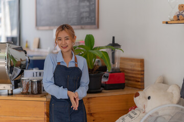 Portrait of Startup successful small Asian business owner in coffee shop. Beautiful Asian woman barista cafe owner.