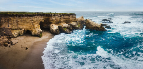 Obraz premium Dramatic coastline landscape, pano. Rocky Cliffs, Pacific Ocean, and native plants on the beach, Montana de Oro State Park, California