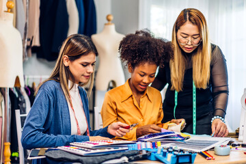 Obraz premium Portrait of young african american woman and young girl fashion designer stylish sitting and working with color samples.Attractive two designer girl work with colorful fabrics at fashion studio