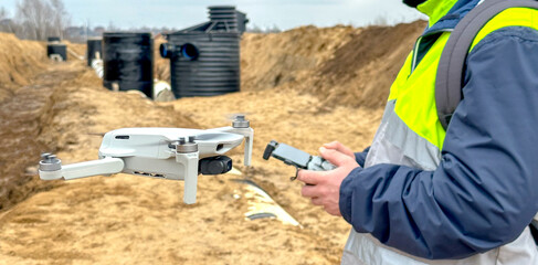 a surveyor engineer with a quadcopter on a construction site