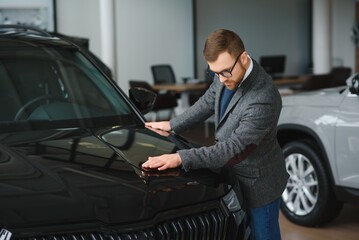 Man adult customer male buyer client wears classic suit white shirt chooses auto wants to buy new automobile touch check car in showroom vehicle salon dealership store motor show indoor. Sales concept