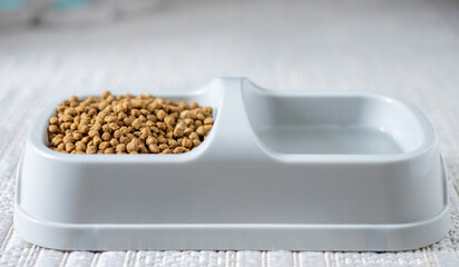 dry cat food isolated on carpet,floor tiles in bowl next to water.domestic pet care,food for kitty kitten