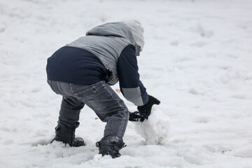 Fototapeta na wymiar A boy makes snow for a snowman