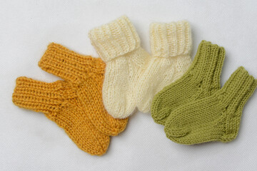 Small baby socks, made of cotton yarn, on white wooden background