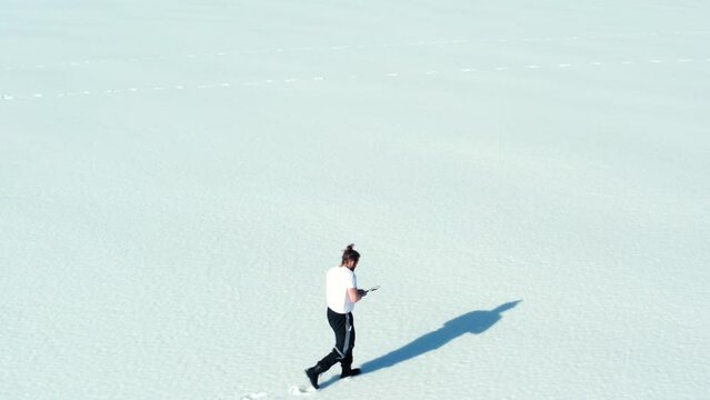 Aerial View Of A Lone Man Walking Through Snow Leaving Foot Marks.