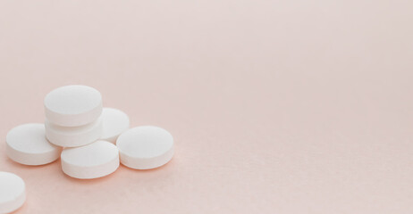 Heap white round pills on pink background with copy space. Health care concept.