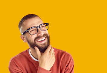 Joyful dreamy man imagining or thinking about something pleasant isolated on orange background....