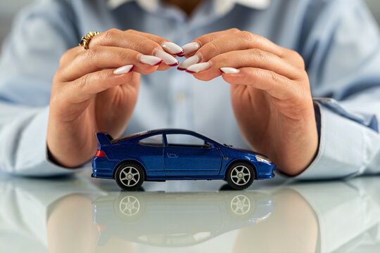 beautiful female hands at the table make conditional protection of a small car.