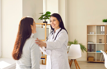 Friendly woman doctor supporting her female patient during medical examination in hospital. Smiling...