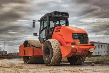Fototapeta na wymiar Road roller at road construction site with cloudy blue sky during sunset.