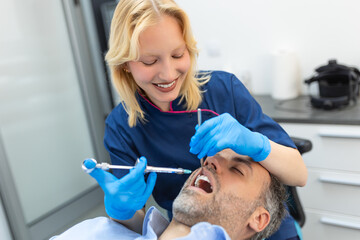 Painkiller anesthesia injection. Dentist examining a patient's teeth in modern dentistry office....