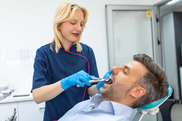 Surgeon removing the tooth. Dentist using surgical pliers to remove a tooth in clinic