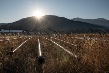Wheelmove irrigation machine in a dry field at the base of the mountains at sunset