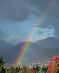 Rainbow over a small town in the mountains on a stormy day