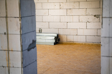 A folded metal profile lies in a room without repair. Building materials for a frame partition in a room. Aerated concrete walls and floors from OSB panels