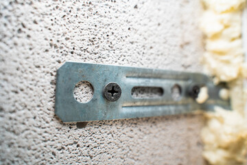 Fastening a window to a wall of aerated concrete bricks close-up. Black self-tapping screw screwed into aerated concrete - obrazy, fototapety, plakaty