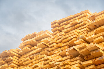 Wooden boards are stored outdoors. Wooden boards, lumber, industrial wood, timber. Pine wood timber stack of natural rough wooden boards on building site.