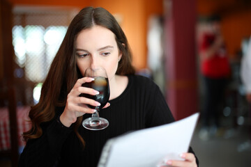 Woman drinking and reading menu in a bar