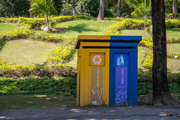 Multicolored recycling bins in the park. Outdoor garbage containers for plastic, paper, glass. Sustainable lifestyle concept. Blue, yellow color