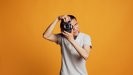 Young professional photographer using dslr camera to take pictures, having fun with photos at photography shoot in studio. Male model posing with equipment, feeling confident.