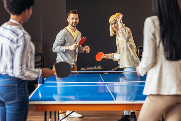 Young people playing table tennis in the office at work