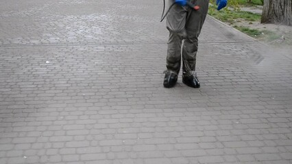 Man in protective suit spraying antiseptic solution on sidewalk in city. Persona disinfecting spray chemicals to preventing spread coronavirus. Sanitary measures in public place. Coronavirus pandemic