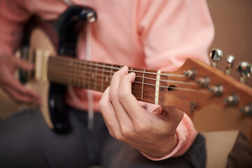 Fototapeta na wymiar Closeup image of young man enjoying playing electric guitar