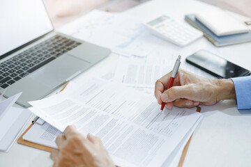 Asian businessman reviewing document reports at office workplace with computer laptop. legal expert, professional lawyer reading and checking financial documents or insurance contract