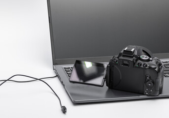 Aparat fotograficzny - lustrzanka cyfrowa z uchylonym ekranem stojąca na laptopie  - obrazy, fototapety, plakaty