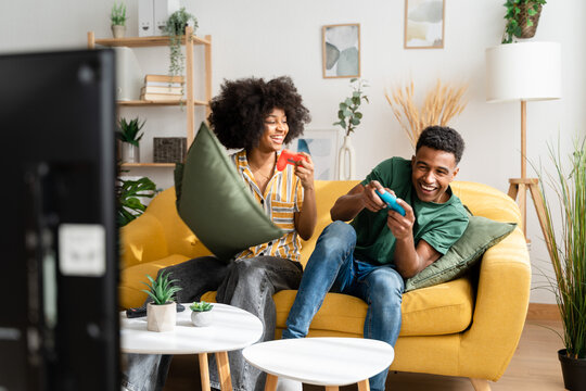 Multiethnic couple playing videogames on sofa