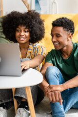 Smiling black couple using laptop at home