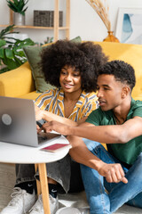 Fototapeta premium Smiling black couple using laptop at home
