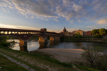 Skyline of Pavia , Ponte Coperto(covered bridge) is a bridge over the Ticino river in Pavia at sunset, Pavia Cathedral background, Italy